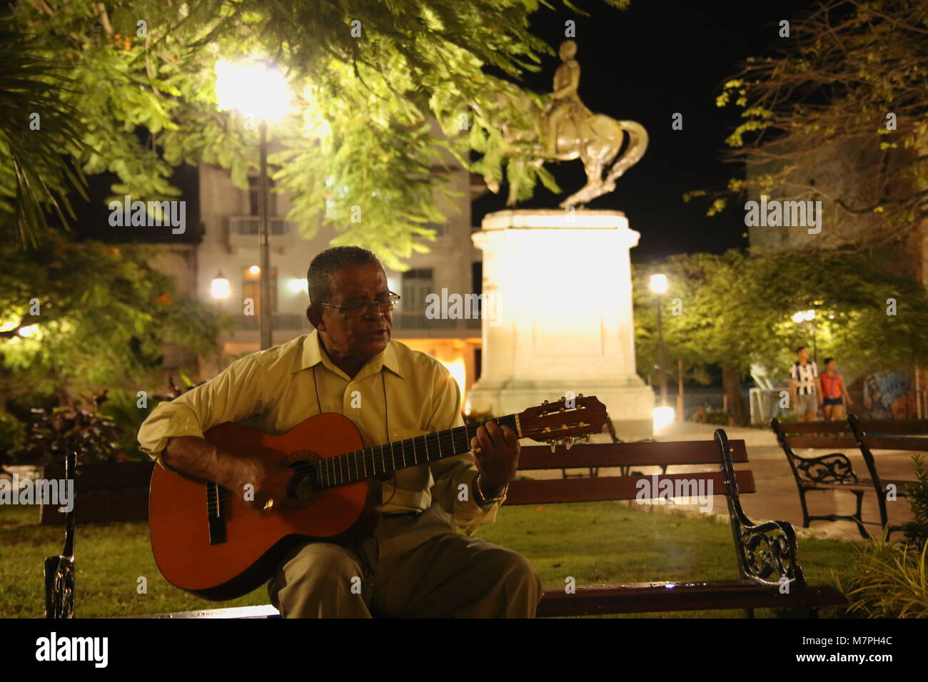 Man on a bench, singing and and playing guitar in Panama City old town at the park at night. Stock Photo