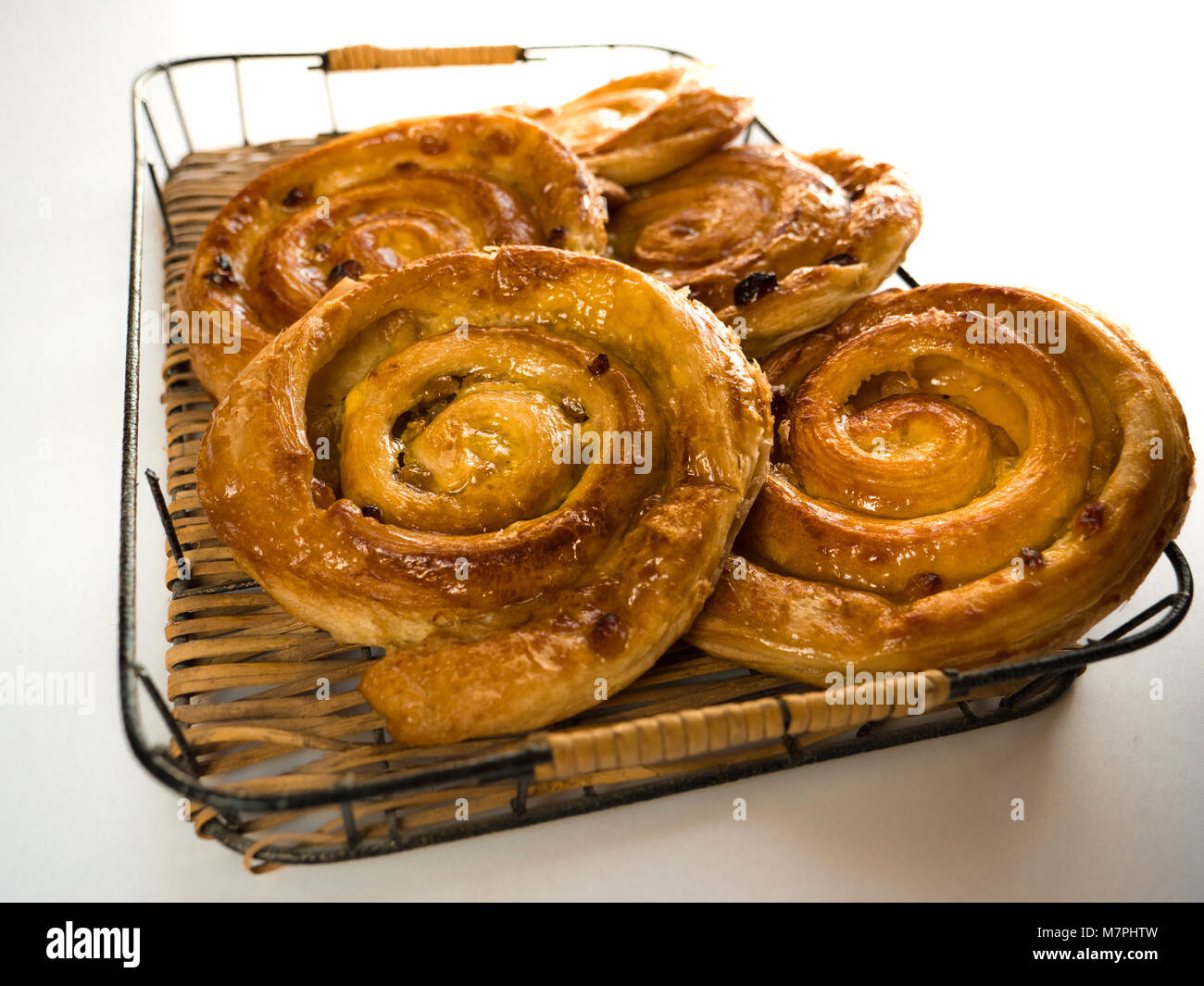 Close up of several French raisin pastries on a wicker trail and white background Stock Photo