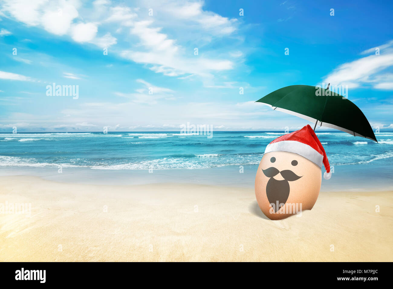 Egg with santa hat in the beach with blue ocean background Stock Photo