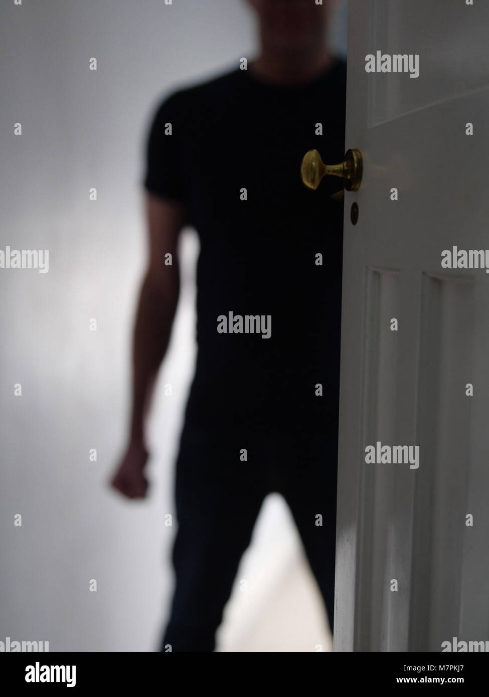 Threatening man in doorway at home with a clenched fist. Domestic violence. Stock Photo