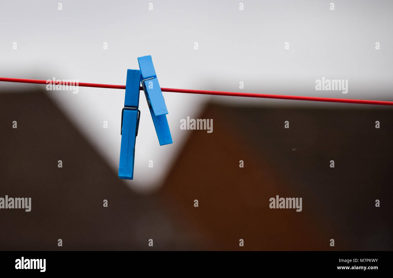 A pair of blue plastic clothes pegs on a red clothes line Stock Photo Alamy