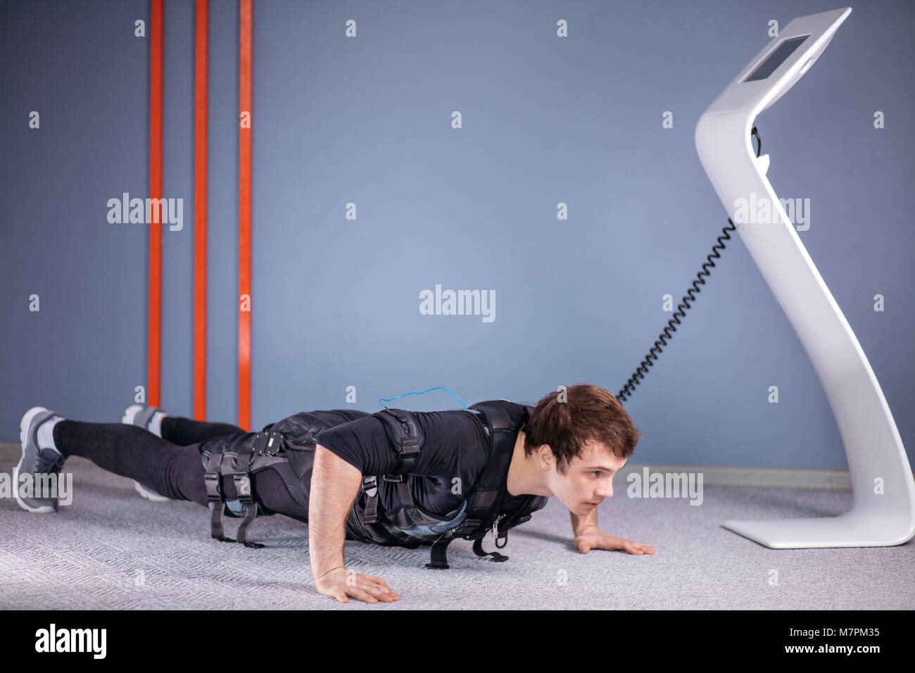 EMS male working out, doing push ups in gym wearing electric muscle