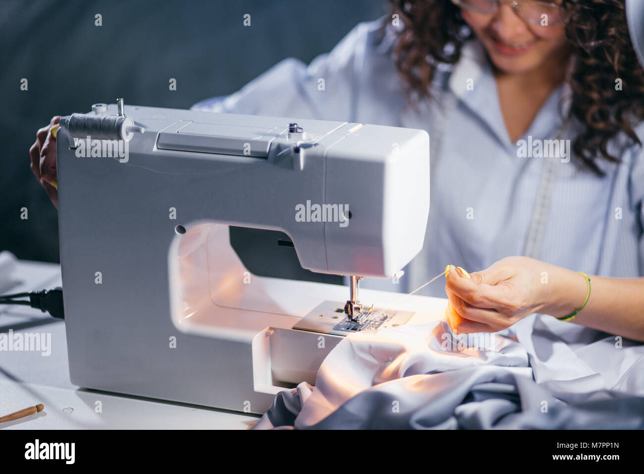 cropped photo of woman stretching tangled thread from sewing machine. changing thread in
