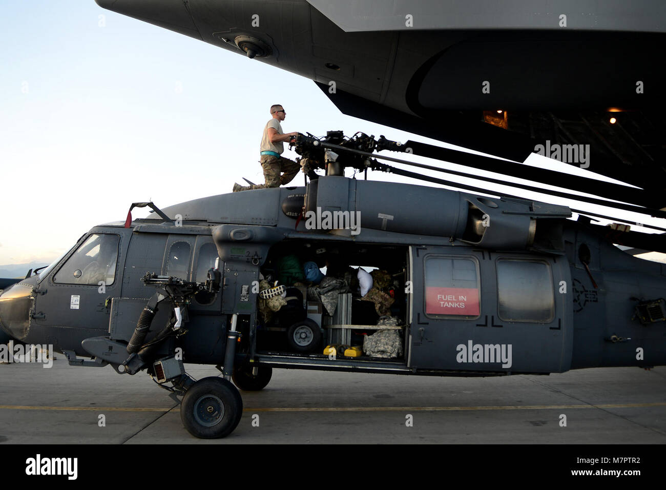 A U.S. Air Force Airman from the 455th Expeditionary Aircraft Maintenance Squadron, directs an HH-60G Pave Hawk helicopter toward a C-17 Globe aircraft at Bagram Airfield, Afghanistan June 9, 2014. The unit is preparing their helicopters for redeployment to their home base, Moody Air Force Base, Georgia. Maintainers here work a non-stop alert schedule and are ready to respond 24 hours a day, seven days a week. (U.S. Air Force photo by Staff Sgt. Evelyn Chavez/Released) 455th Air Expeditionary Wing Bagram Airfield, Afghanistan Stock Photo