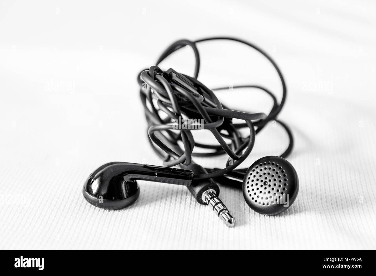 Black headphones tangled isolated on white background Stock Photo