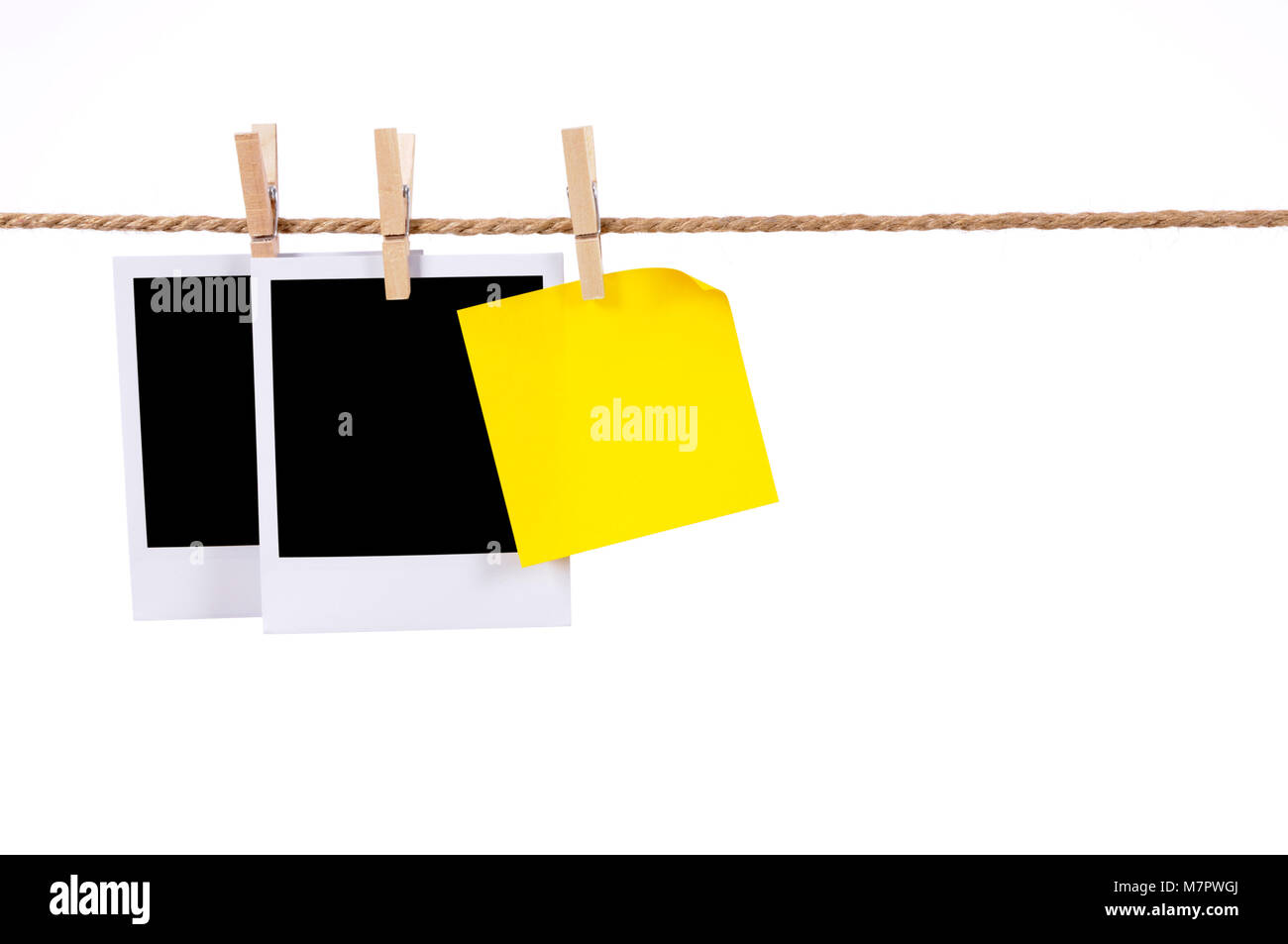 Blank instant camera photo prints and an office sticky note hanging on a rope or string isolated against a white background.  Space for copy. Stock Photo