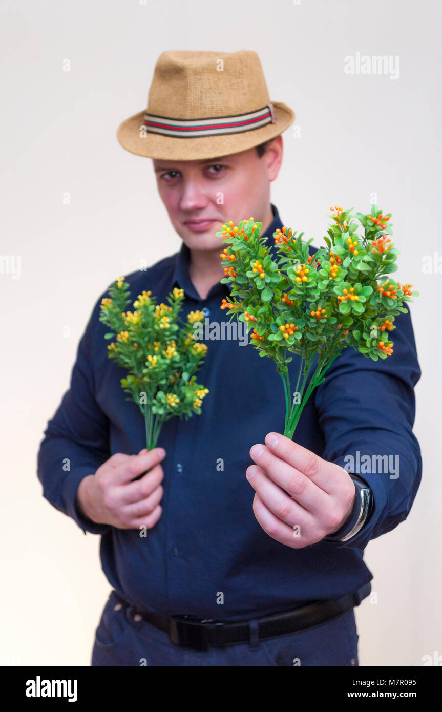 Portrait of young elegant man with blue shirt and summer hat holding