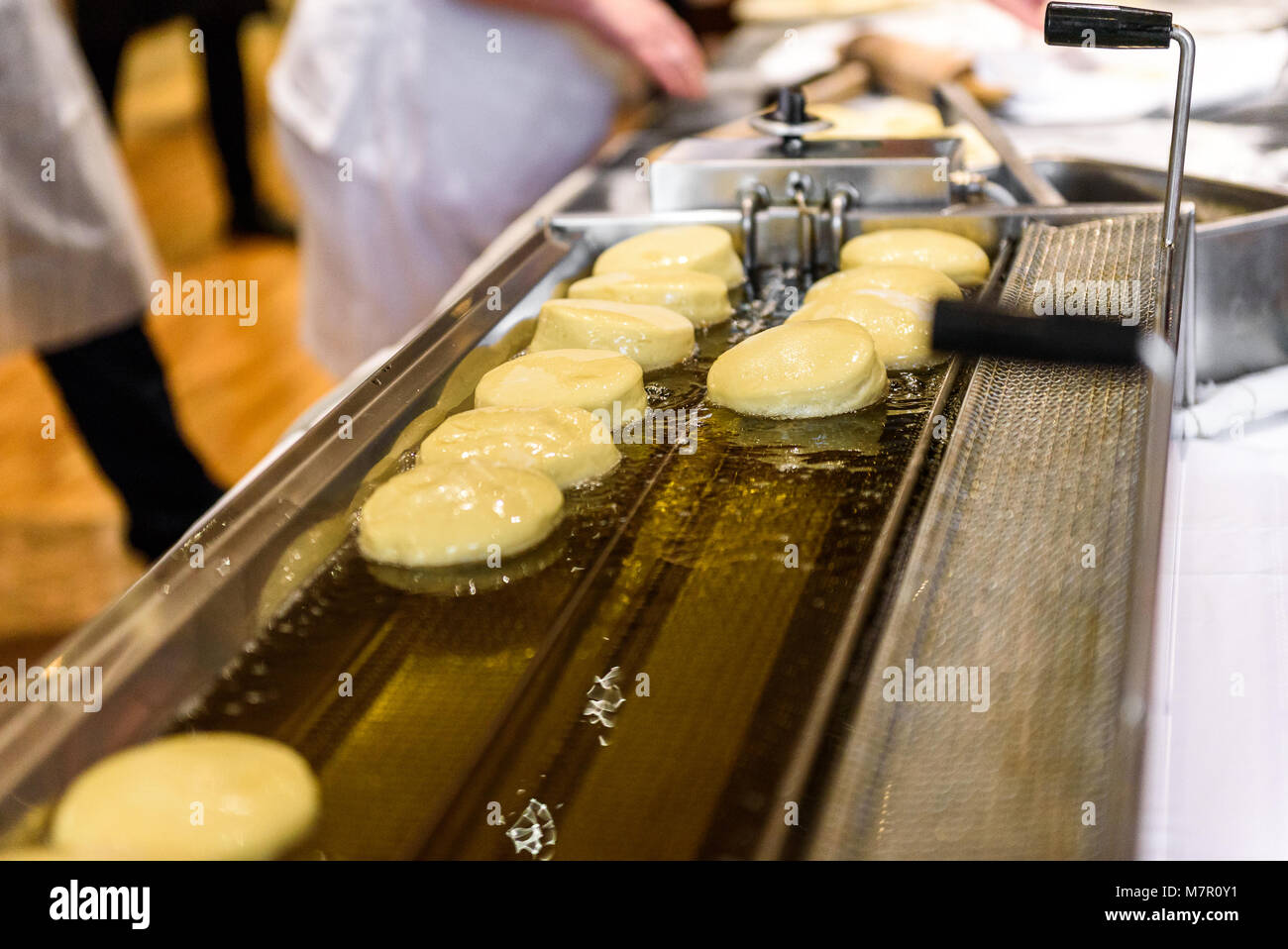 Making homemade jam doughnuts in a professional restaurant buffet kitchen. Deep frying doughnuts