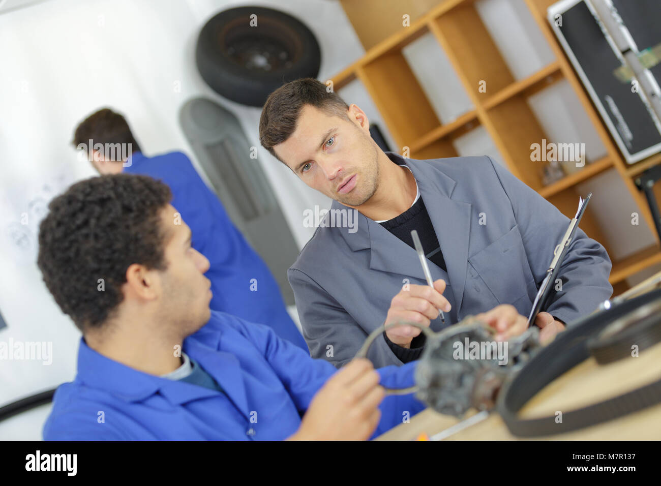 mechanic and apprentice working on car piece Stock Photo - Alamy