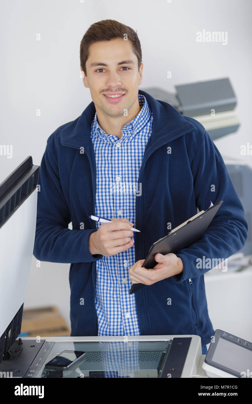 portrait of man at photocopier holding clipboard Stock Photo Alamy