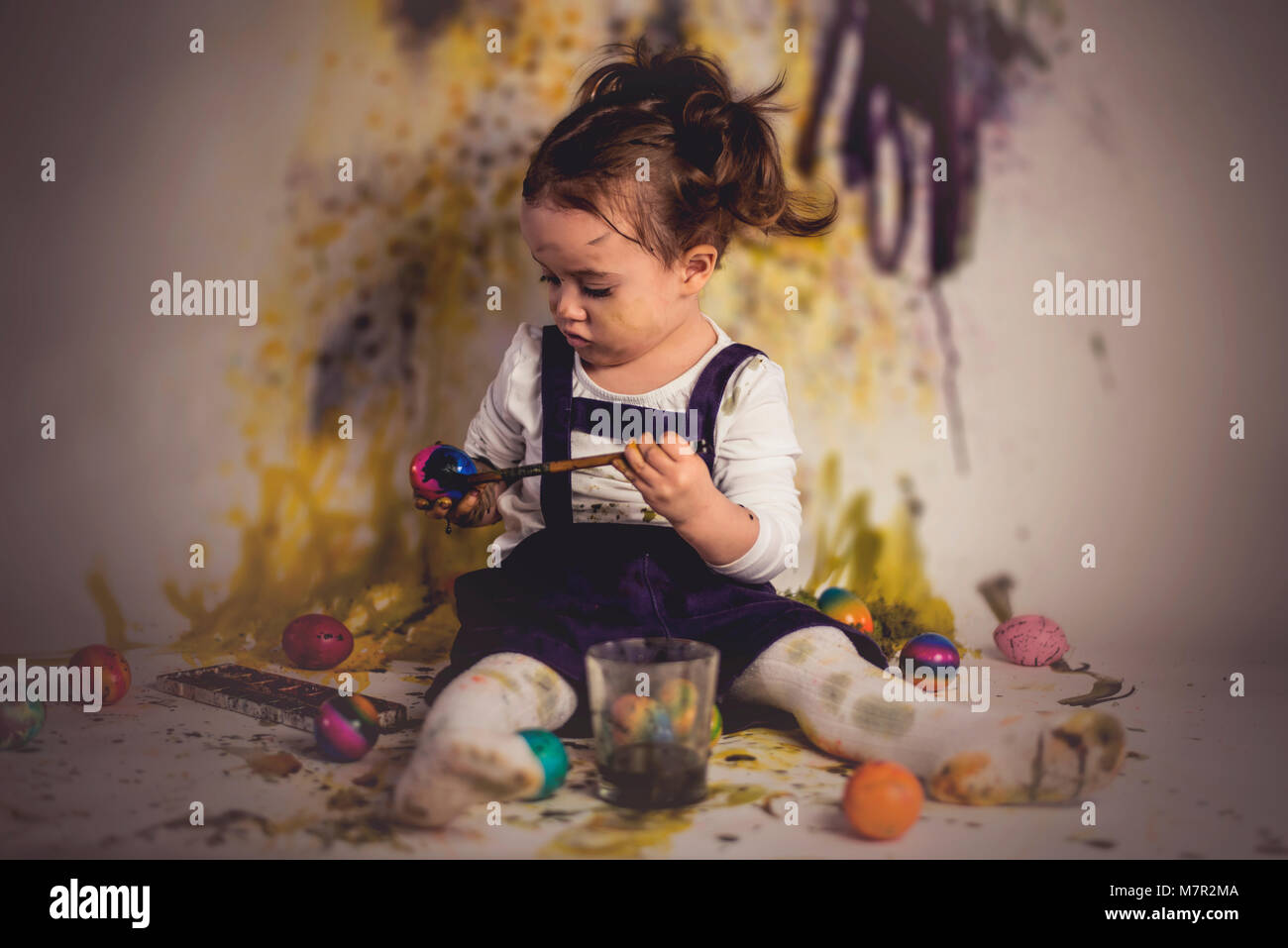 Cute little child girl is painting easter eggs. Stock Photo