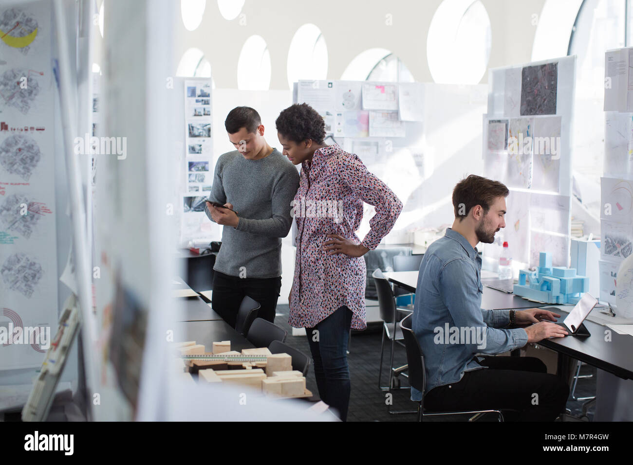 Designers looking at smartphone in creative workspace Stock Photo