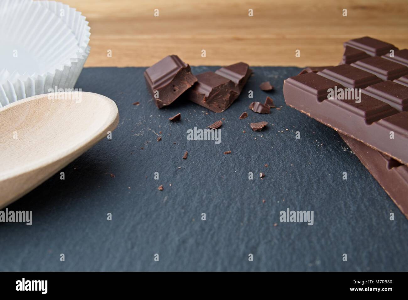 Broken plain chocolate with baking utensils on slate background Stock Photo