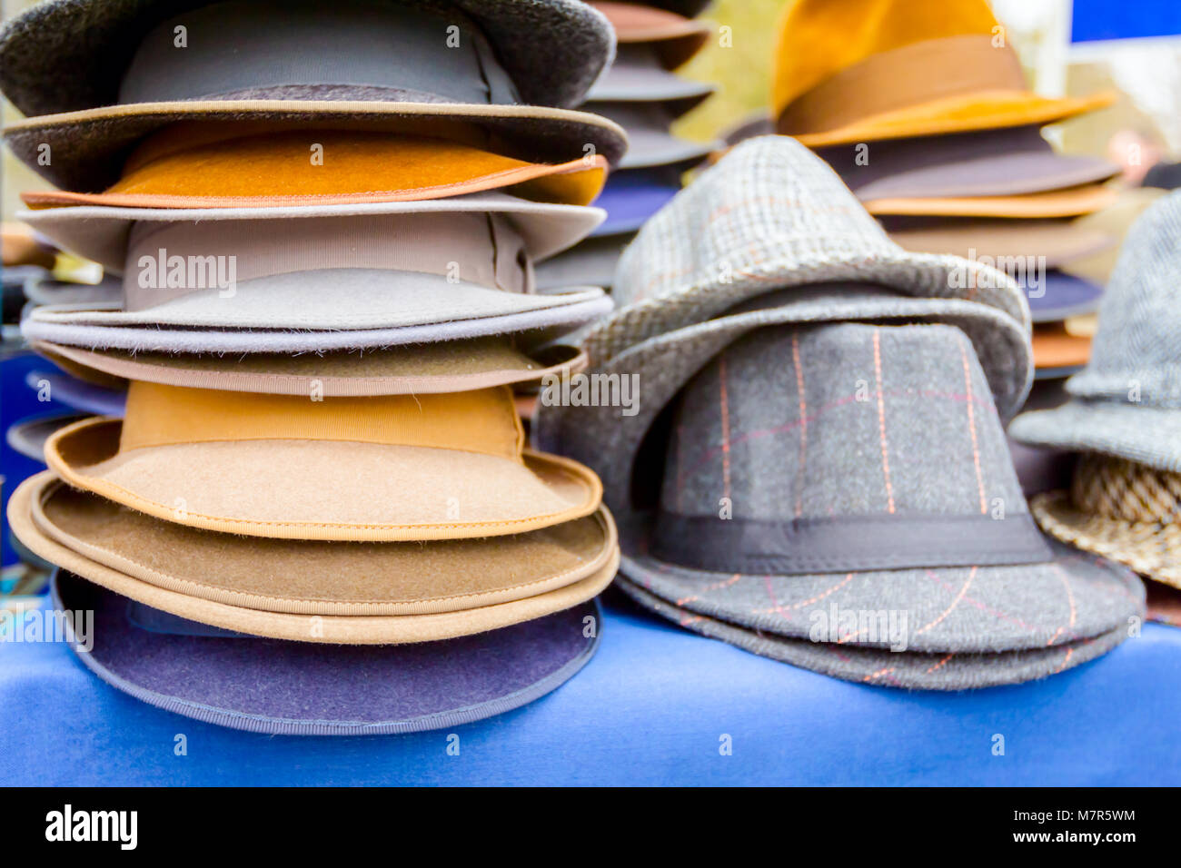 Stacked various colored men hats for sale, available at flea market