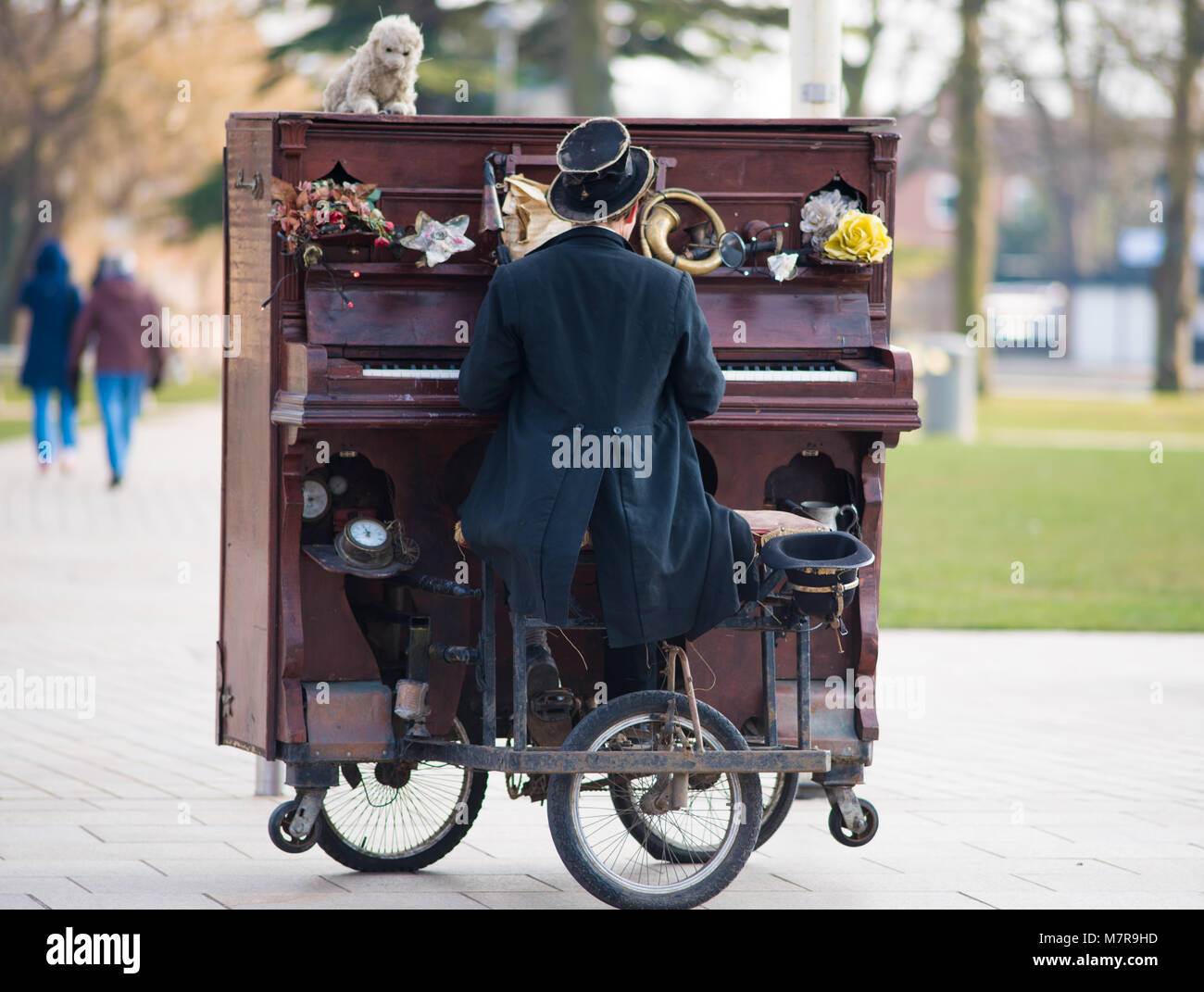 entertainer in Victorian coat tails and top hat playing upright moveable  piano on wheels in street Stock Photo - Alamy