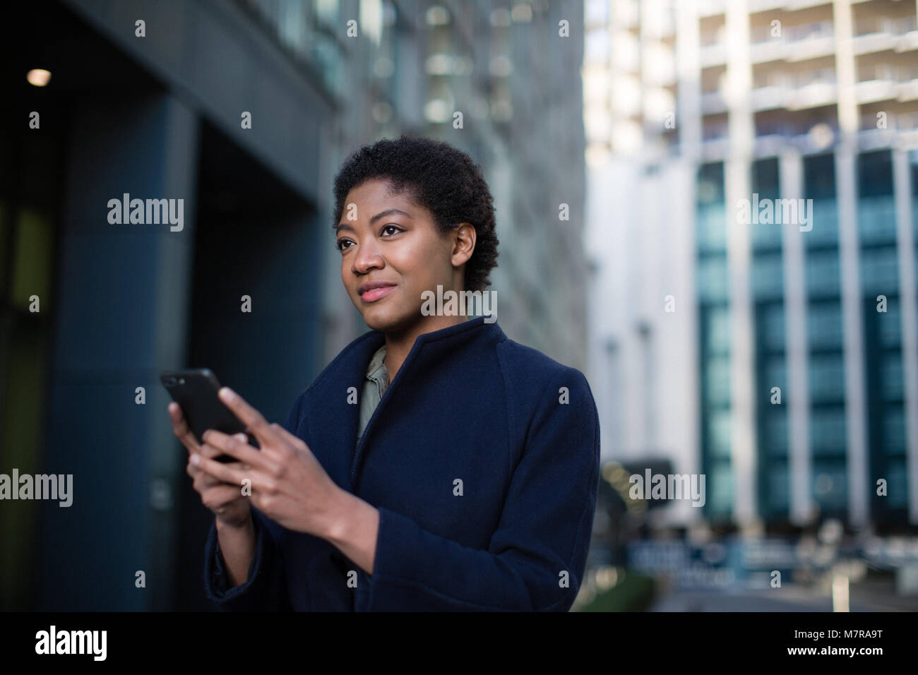 Young adult female checking smartphone in city Stock Photo