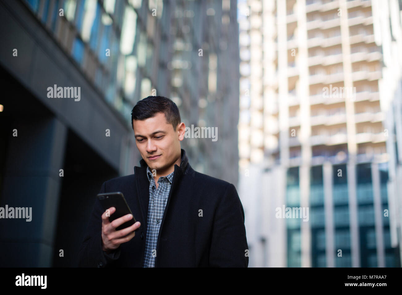 Young adult male checking smartphone in city Stock Photo