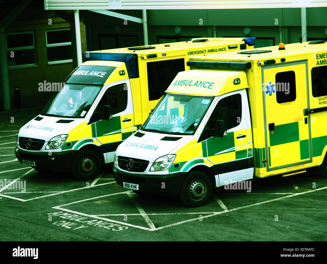 Two ambulances waiting outside an A&E department of a hospital in a cross-processed effect Stock Photo