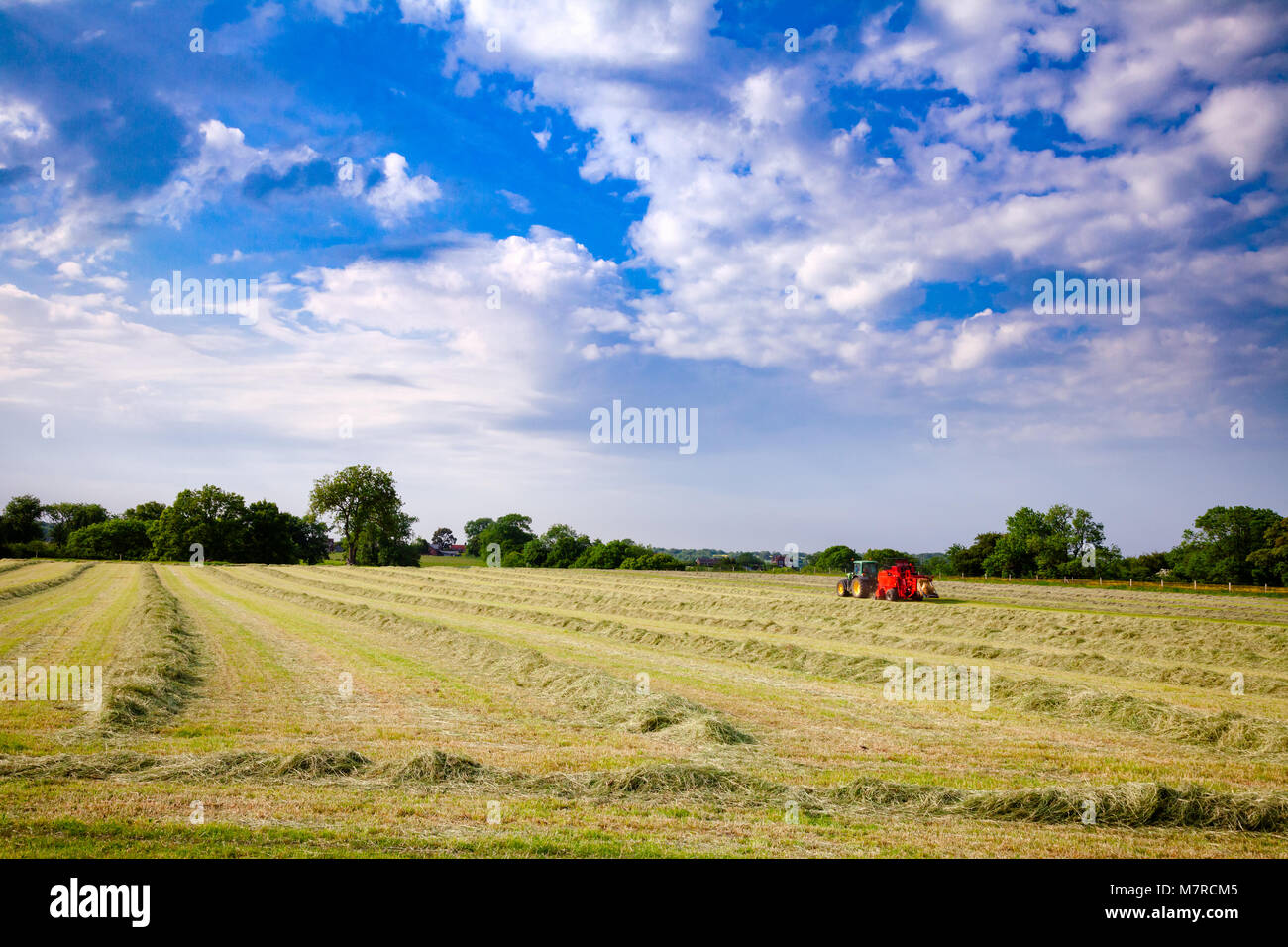 English rural landscape with  tractor collecting cut hay making silage bales Southern England UK Stock Photo
