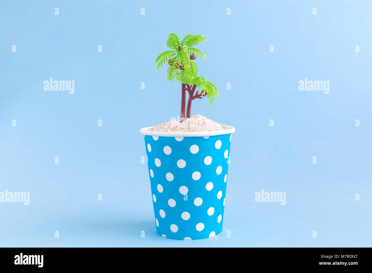 Paper cup polka design with sand and palm tree on pastel blue ...