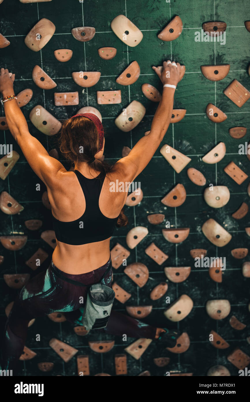 Woman climbing wall at an indoor wall climbing centre. Rock climber