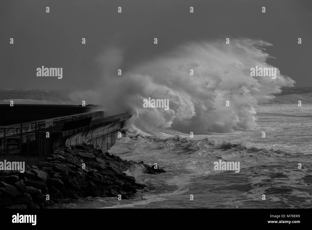 Big storm waves reach a breakwater structure in a pier in the Atlantic coastline. Cascais Portugal Stock Photo