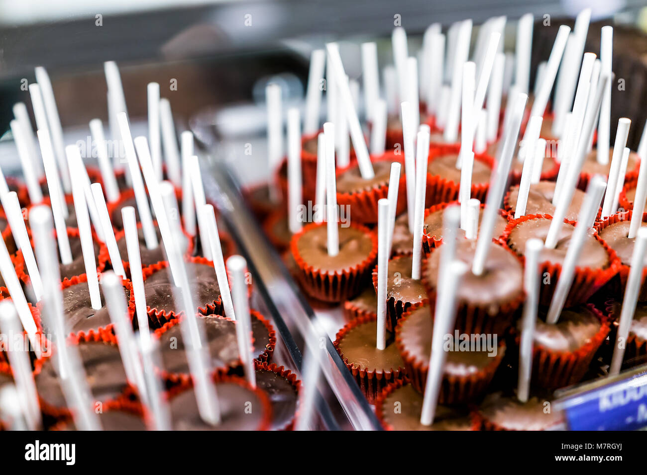 Closeup of milk brown dark chocolate cake pops lollipos on sticks in red  muffin paper liners on display in candy store shop cups truffles Stock  Photo - Alamy