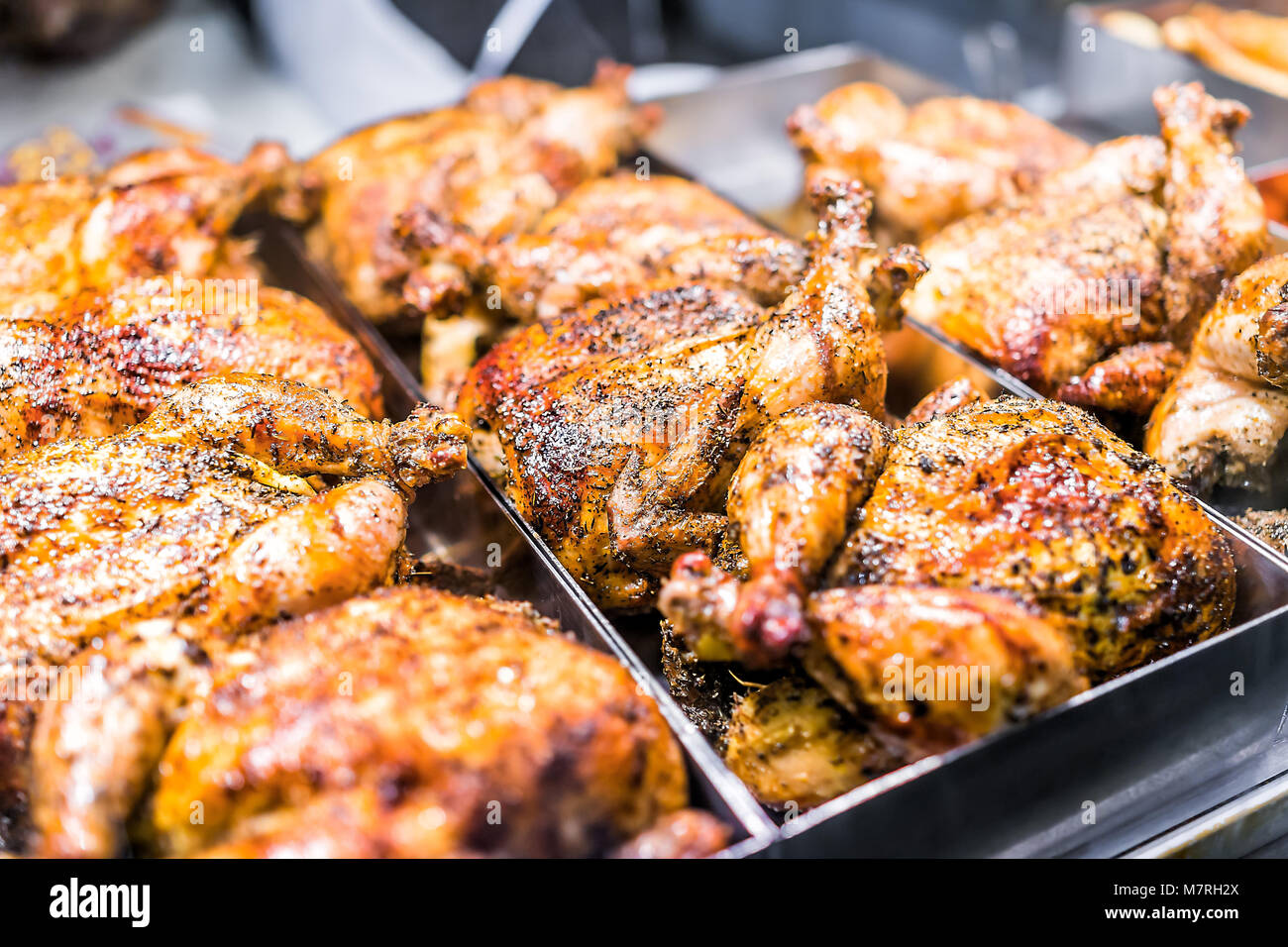 Many whole chicken roasted closeup on tray in deli display store shop grocery brown with herbs, golden skin, spices, crispy Stock Photo