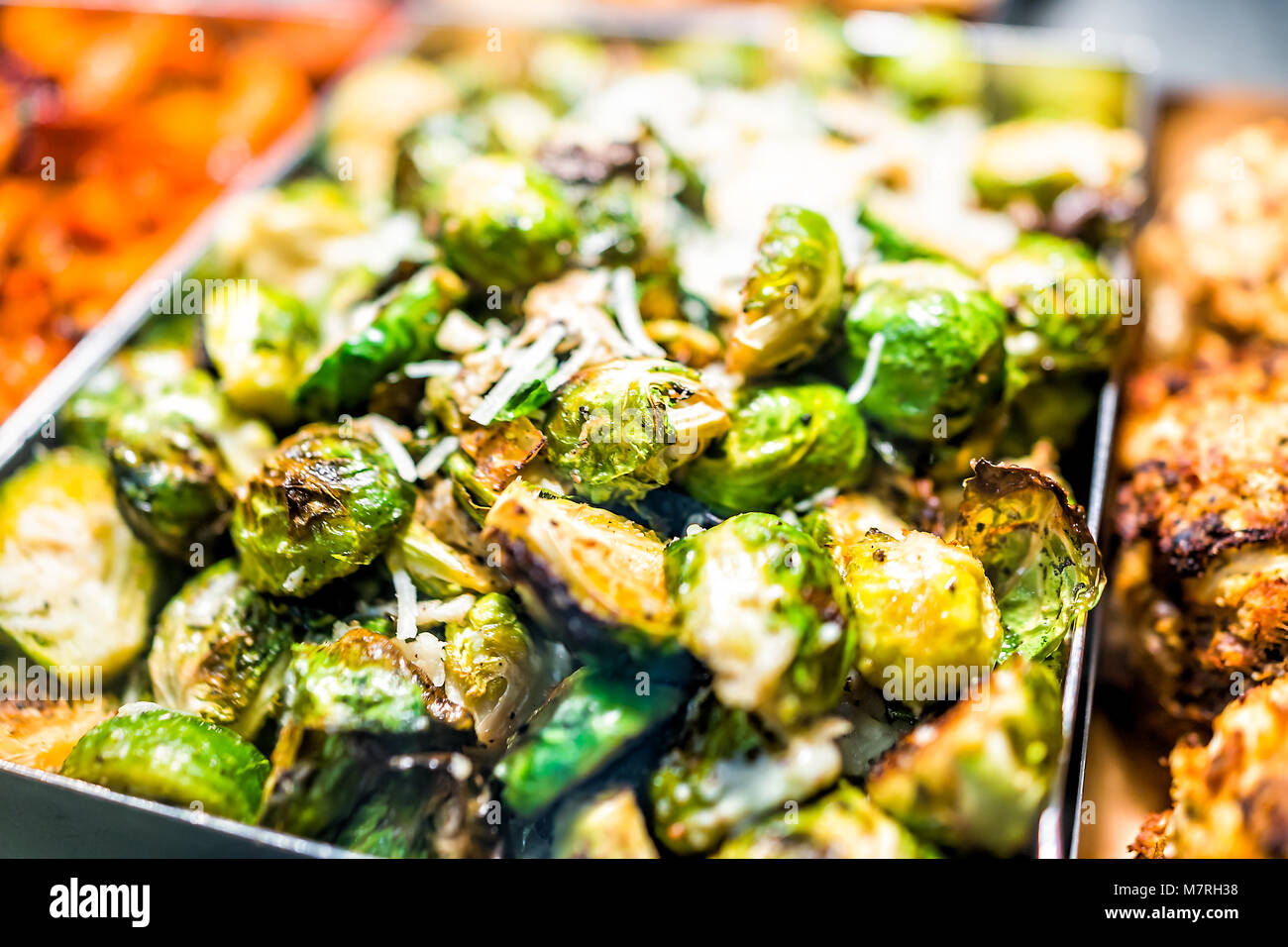 Macro closeup of roasted green brussels sprouts cabbage in tray on display in buffet, catering, deli, store, shop grocery market fresh, cheese Stock Photo