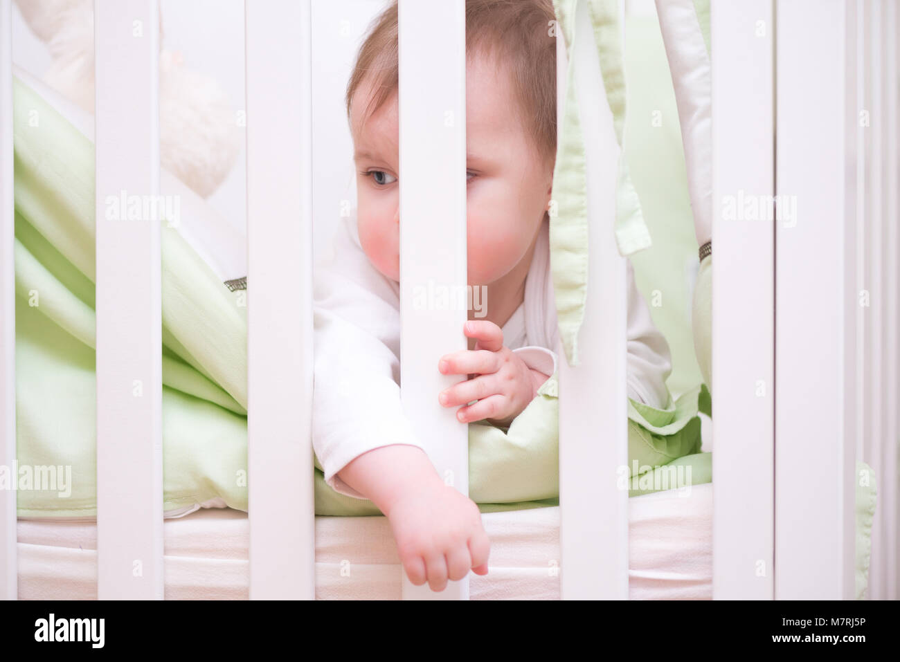 Bored baby in a white wooden crib Stock Photo Alamy