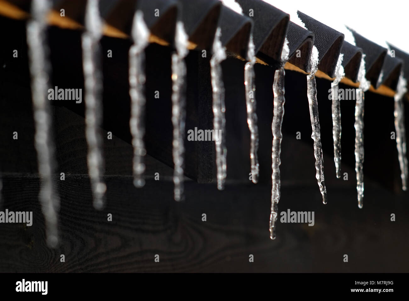 Icicles hanging from a shed roof. Stock Photo