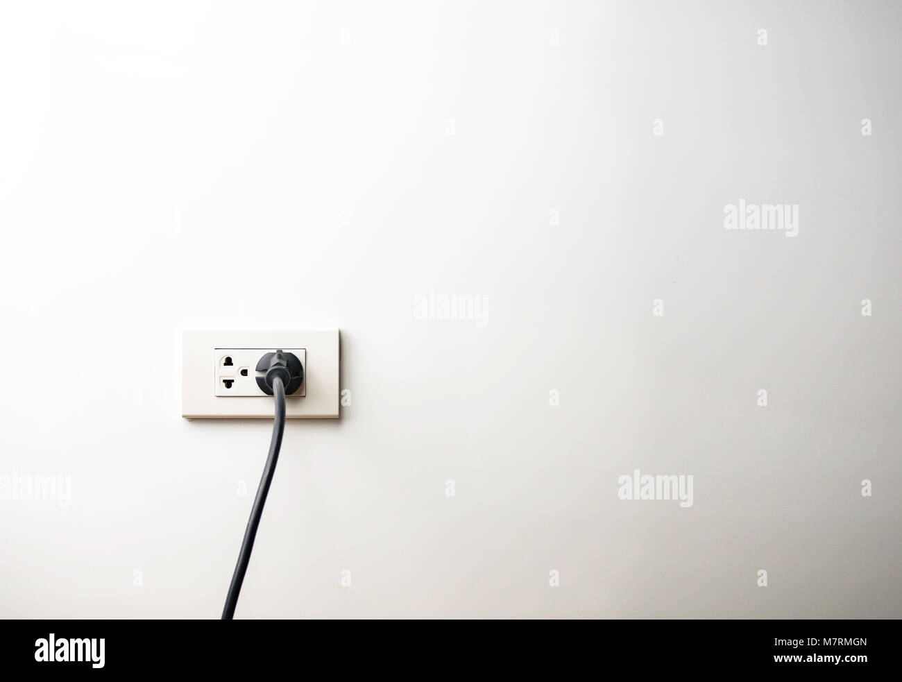 Black electric cord plugged into a socket Stock Photo Alamy