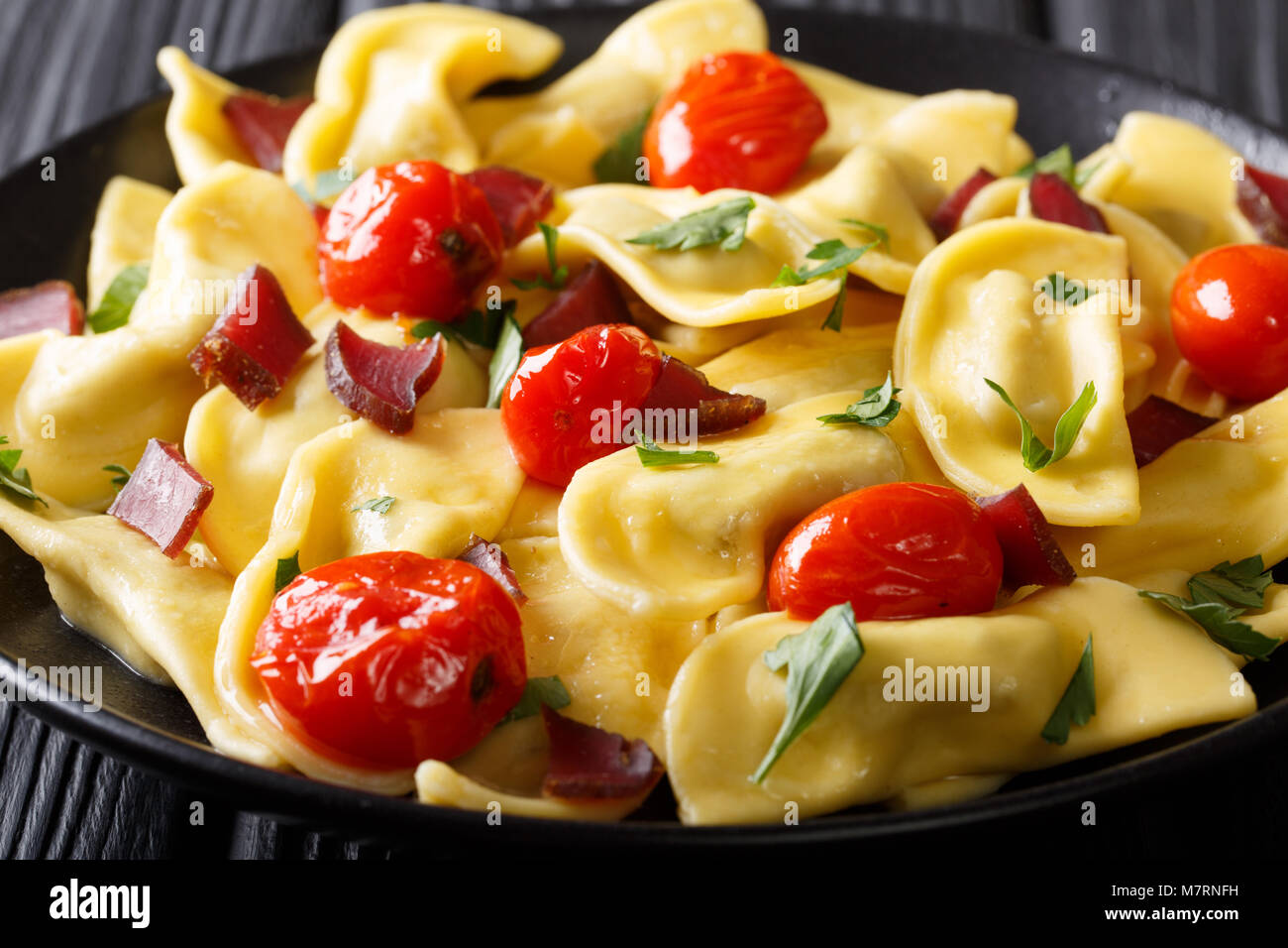 Traditional Italian pasta casoncelli with prosciutto filling, with cherry tomatoes close-up on a plate. horizontal Stock Photo