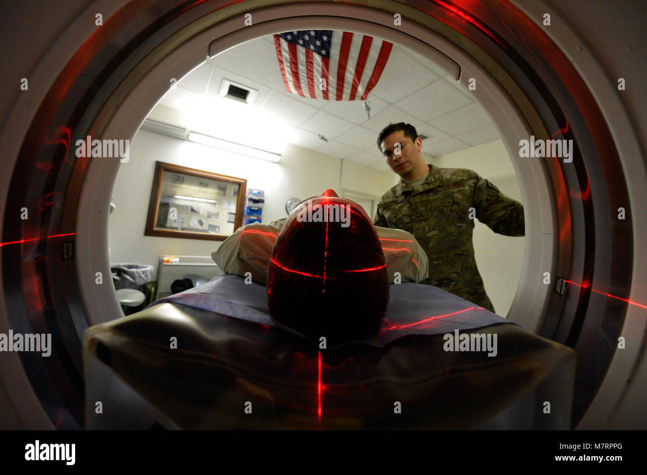 U.S. Air Force Senior Airman Freddy Toruno, 455th Expeditionary Medical Support Squadron diagnostic imaging technologists, positions a service member for a CT scan at Bagram Airfield, Afghanistan’s Craig Joint Theater Hospital July 24, 2014.  The CT scan helps radiologists diagnose different types of disease and injuries, such at traumatic brain injuries.  Toruno is deployed from Travis Air Force Base, Calif. and a native of Miami, Fla.  (U.S. Air Force photo by Staff Sgt. Evelyn Chavez/Released) 455th Air Expeditionary Wing Bagram Airfield, Afghanistan Stock Photo