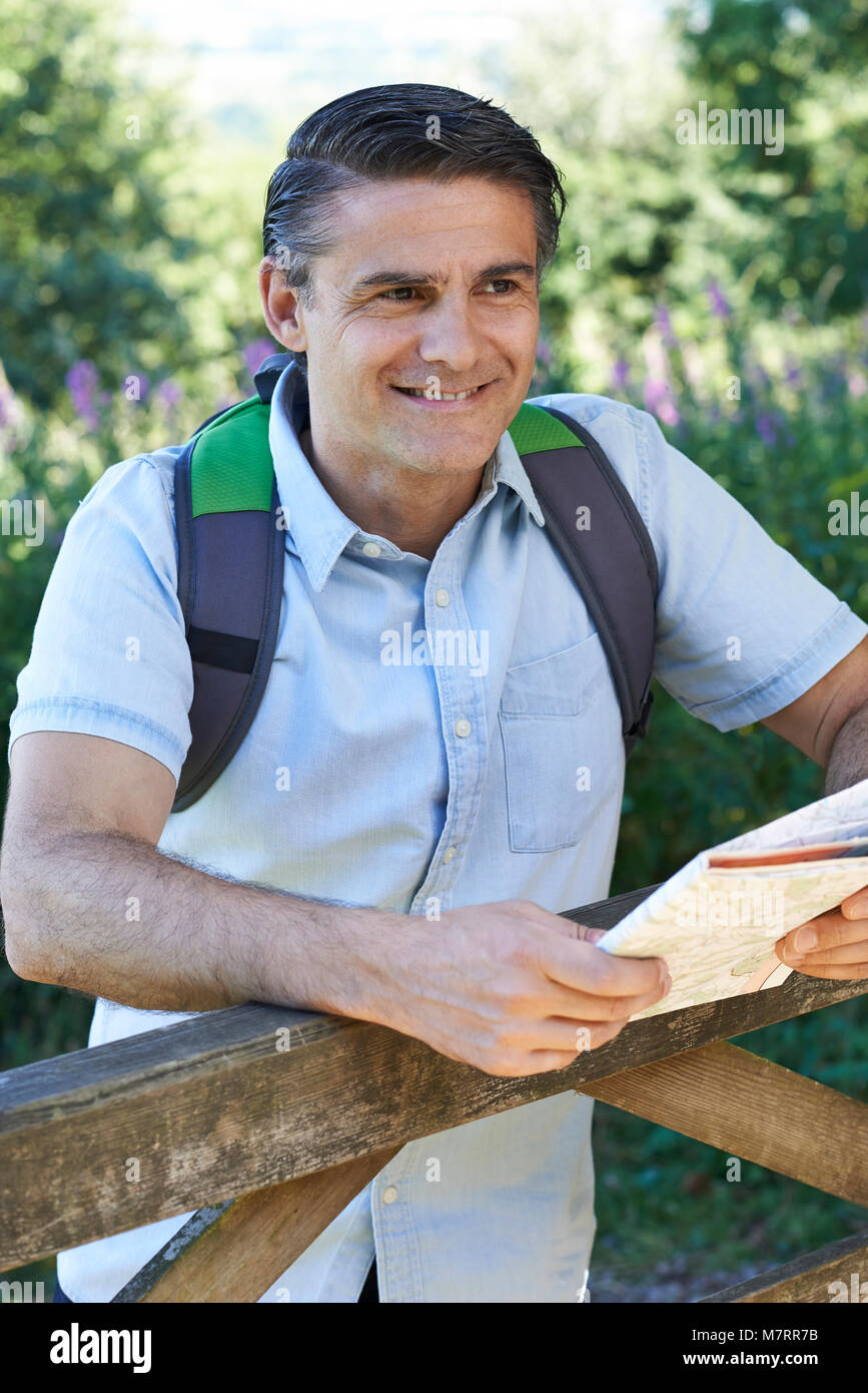 Mature Man Hiking In Countryside Looking At Map Stock Photo