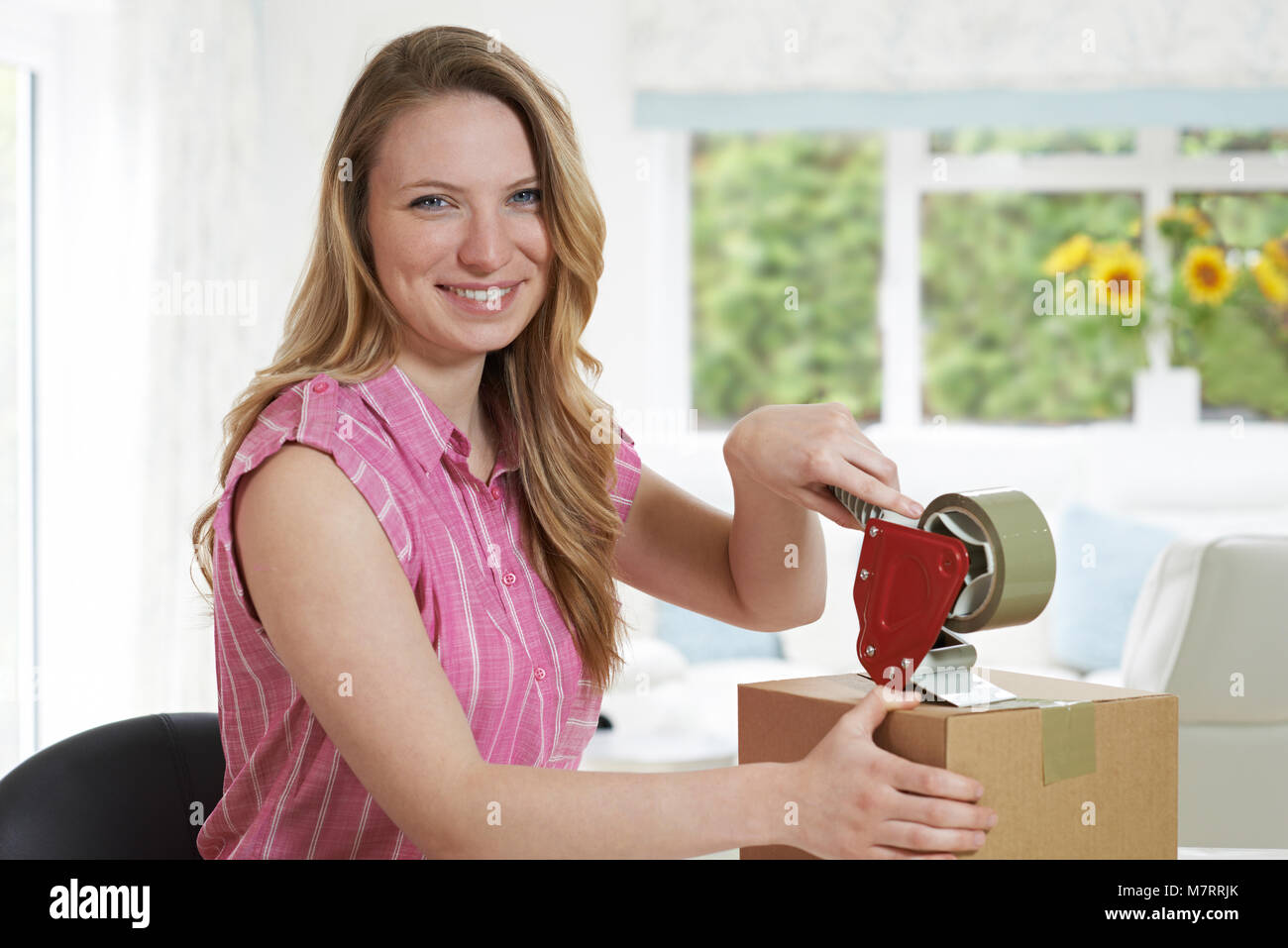 Portrait Of Woman At Home Sealing Box For Dispatch Stock Photo