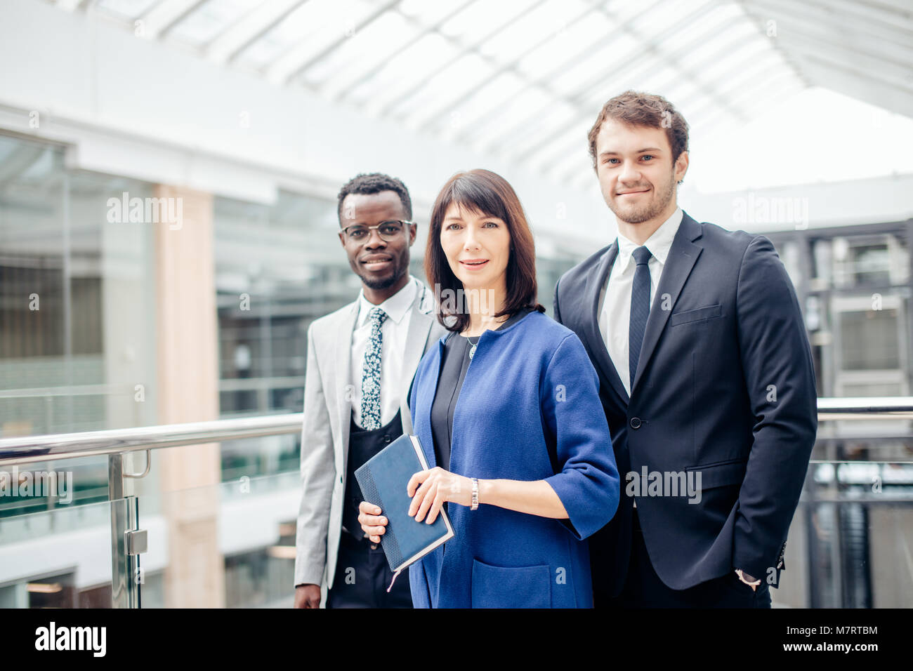 group of businesspeople standing together in office and looking at ...