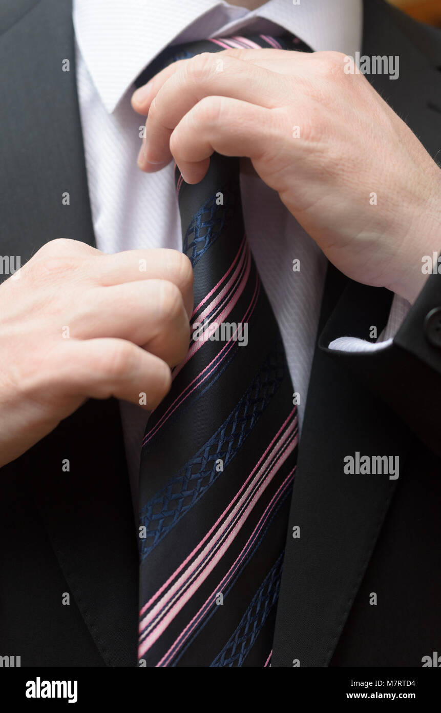 Businessman in a business suit straightens his tie Stock Photo - Alamy