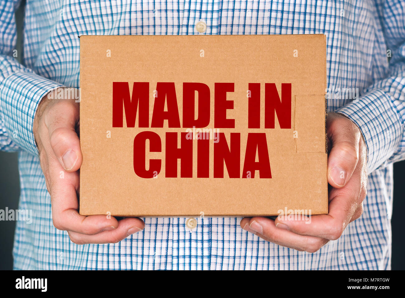 Man holding cardboard box product package with Made in China label imprint for merchandise goods imported from East Asia Stock Photo