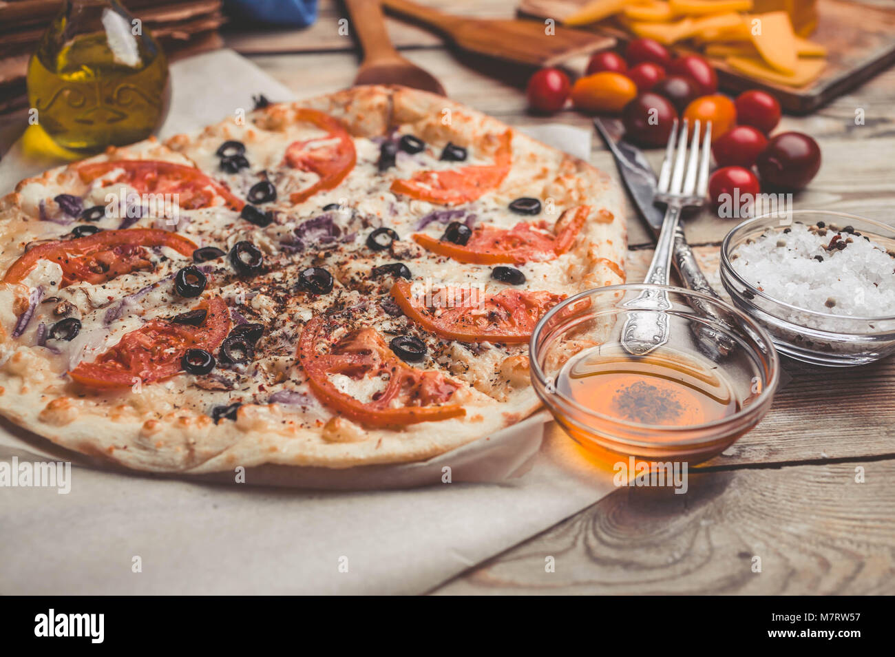 Pizza Margarita on thin crust. Food composition on a wooden background. Mediterranean traditional cuisine. Easy vintage toning Stock Photo