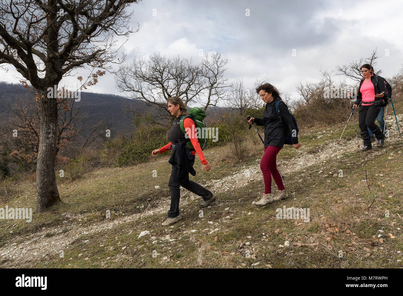 Monte San Giovanni in Sabina, Italy - March 10, 2018: A group of hikers explore mountain paths, among oak and holm oak woods. The scene is composed of Stock Photo