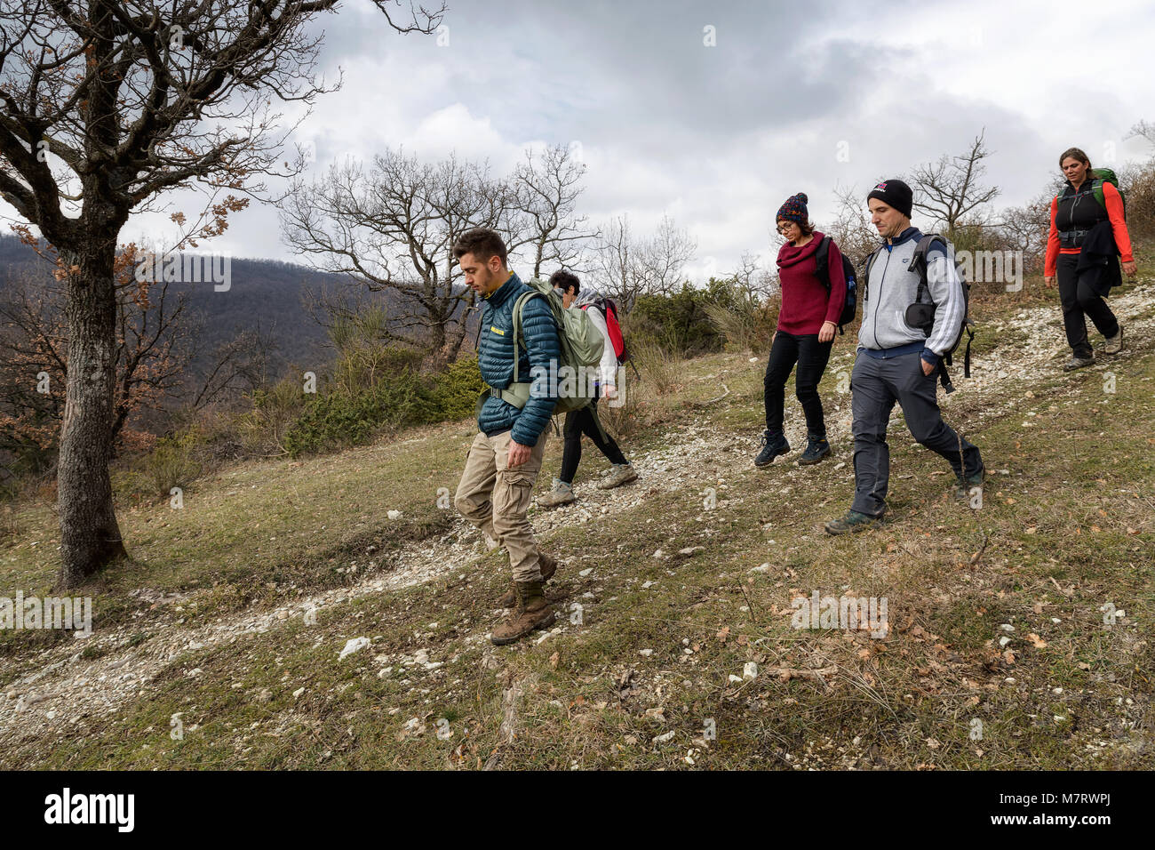 Monte San Giovanni in Sabina, Italy - March 10, 2018: A group of hikers explore mountain paths, among oak and holm oak woods. The scene consists of fi Stock Photo