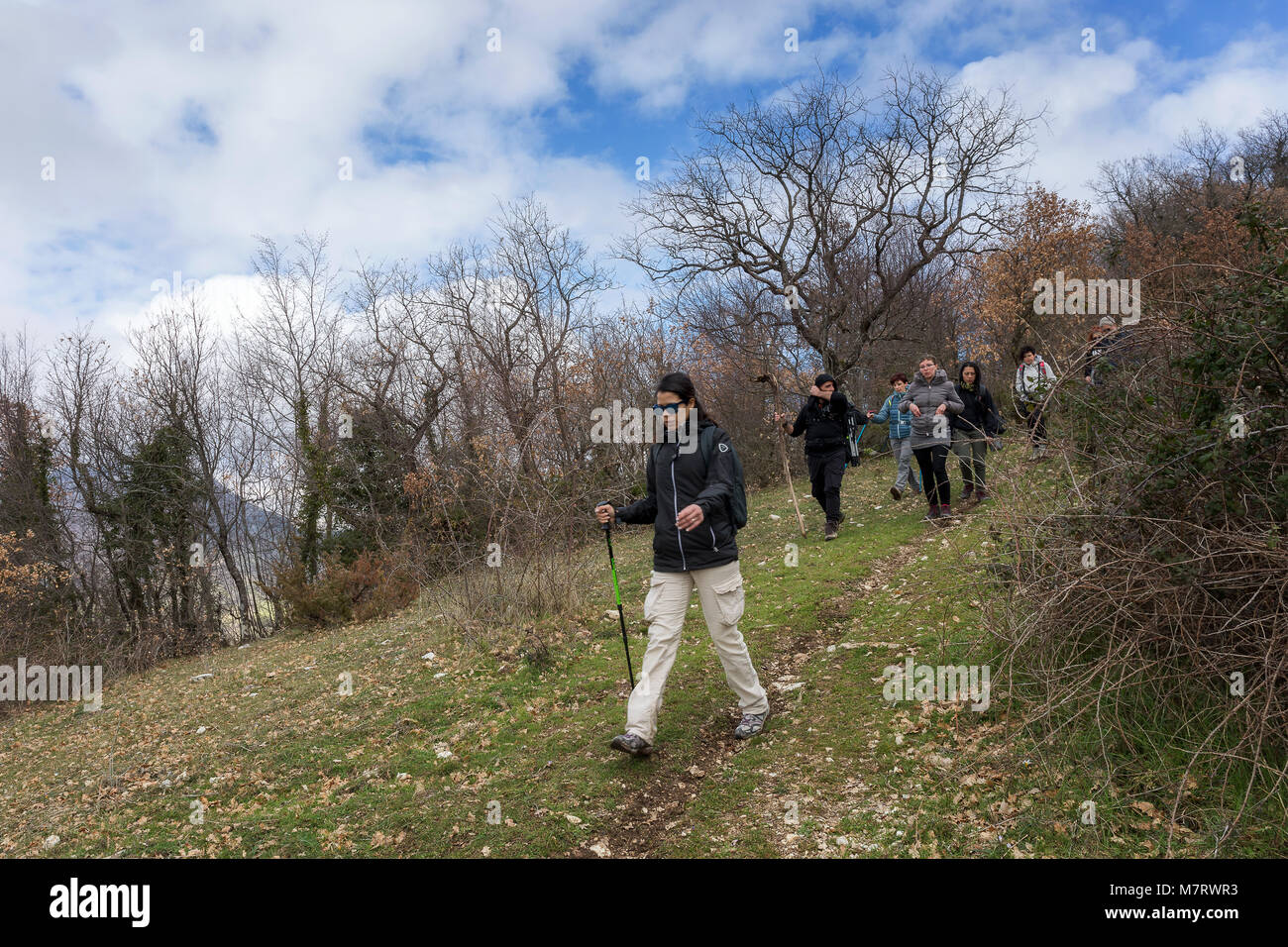 Monte San Giovanni in Sabina, Italy - March 10, 2018: A group of hikers explore mountain paths, among oak and holm oak woods. In the foreground, girl  Stock Photo