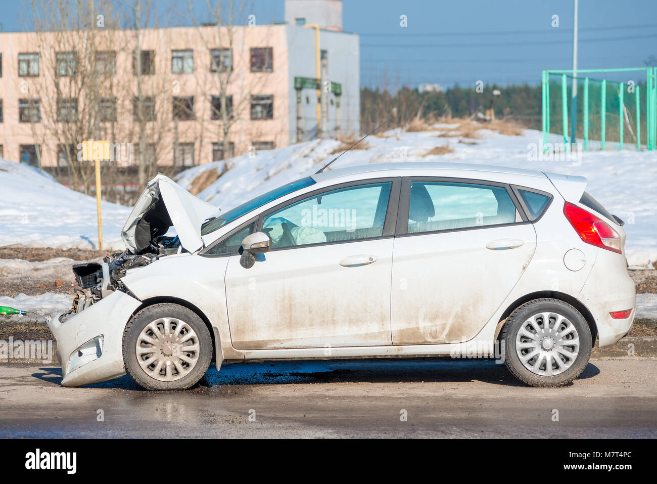 side view of a white car with a broken front on the road in the city ...