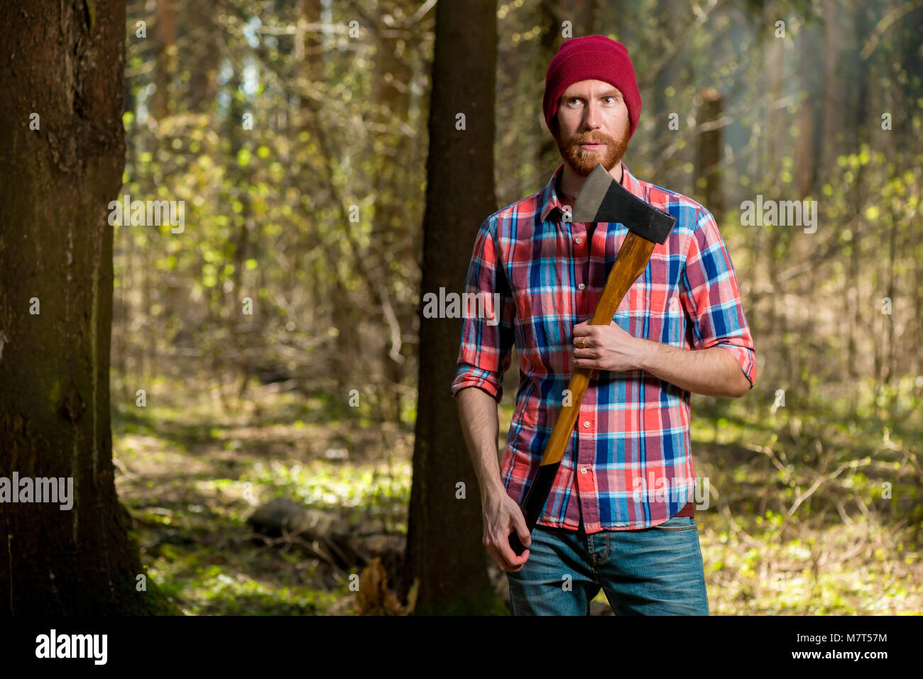 portrait of a bearded hipper forest ranger in a forest with an ax Stock Photo