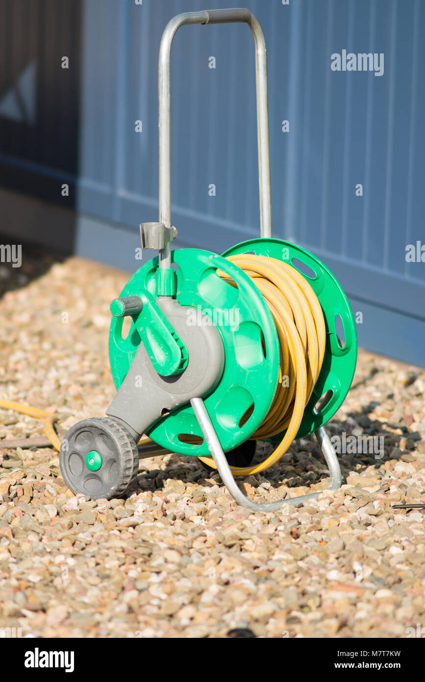 green and yellow garden hose pipe on reel with sheds in background
