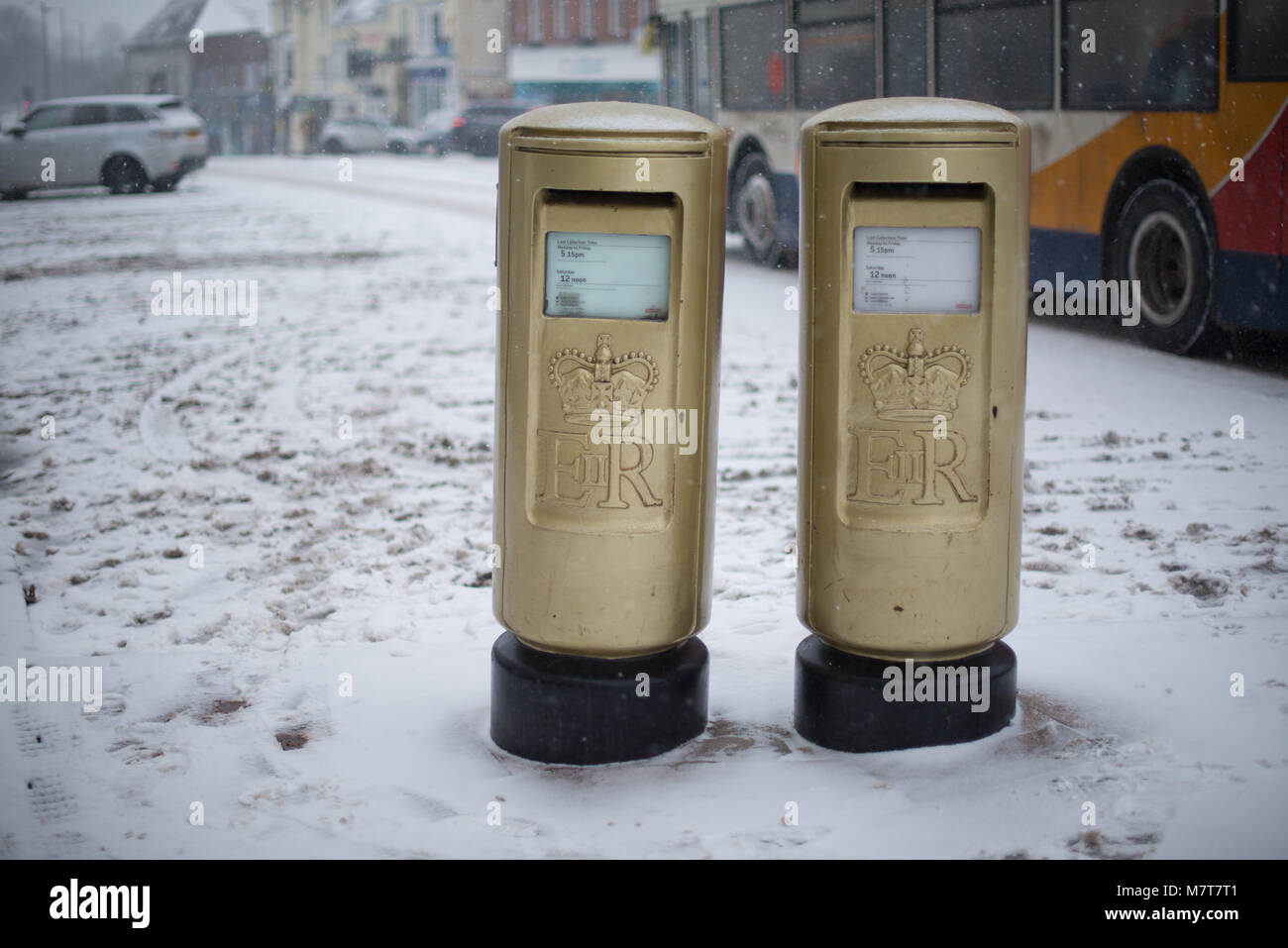 pair of golden post boxes in the UK to celebrate 2012 Olympic gold medal wins from Team GB during winter covered in snow Stock Photo