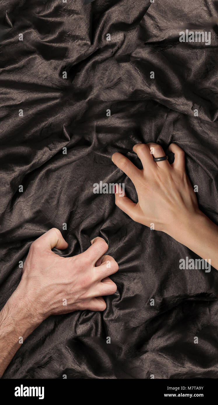 couple's hand holding a satin sheet, a moment of pleasure Stock Photo