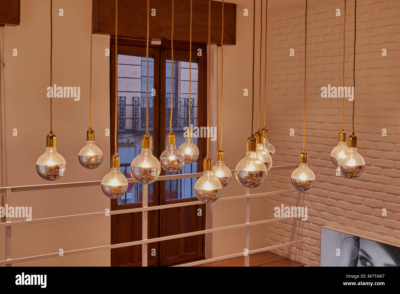 Set of vintage glowing light bulbs with gilded caps and wires hanging from the ceiling in Toledo Stock Photo