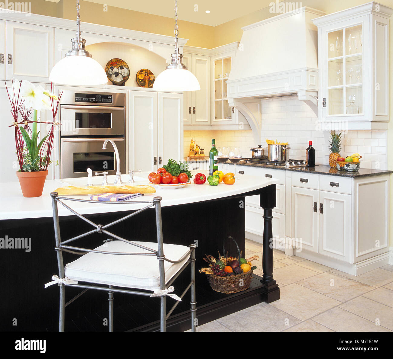 Beautiful White Kitchen With Vegetables on island countertop Stock Photo